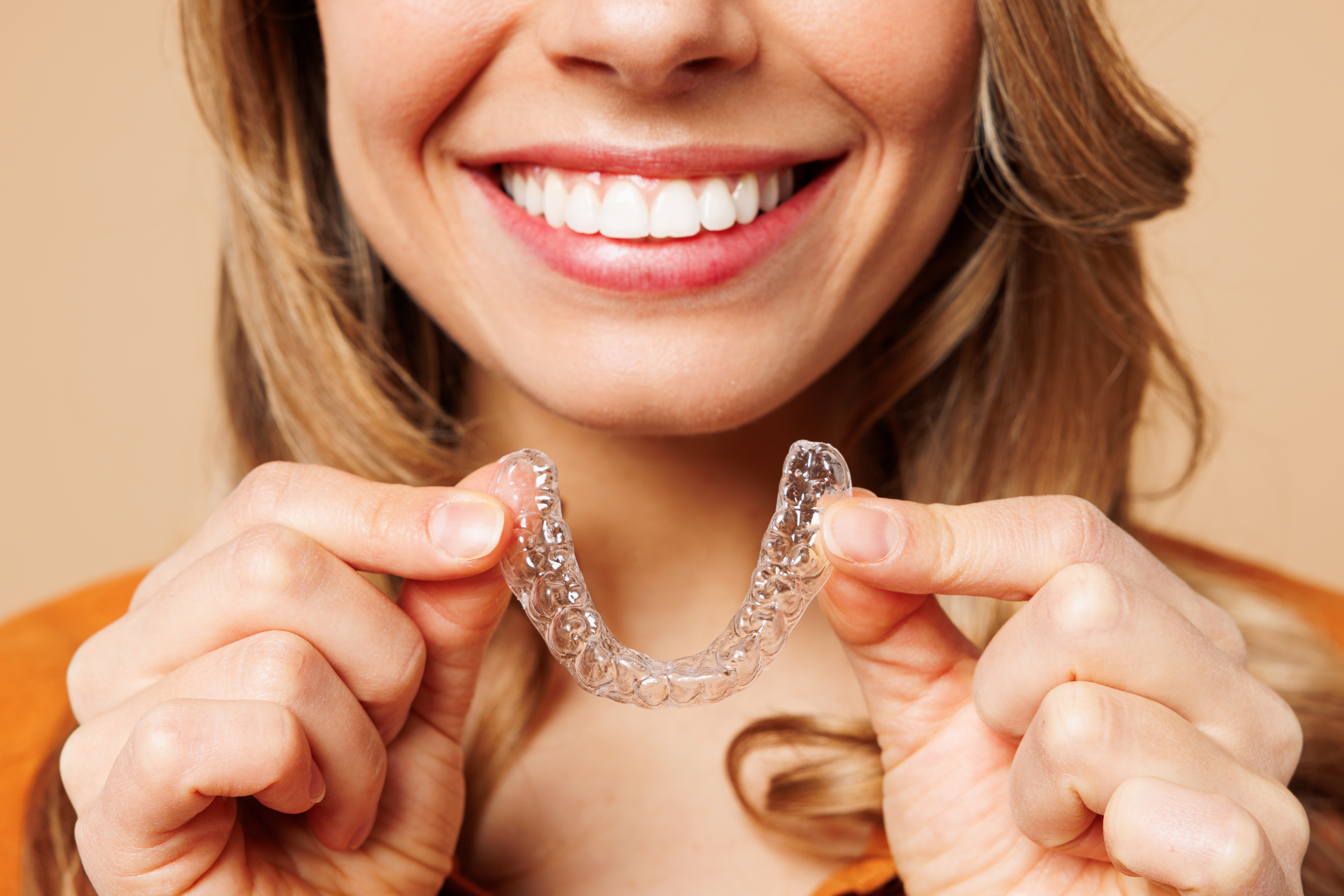 Adult woman smiles after completing her 9 months of Invisalign treatment for a straight, aligned teeth.